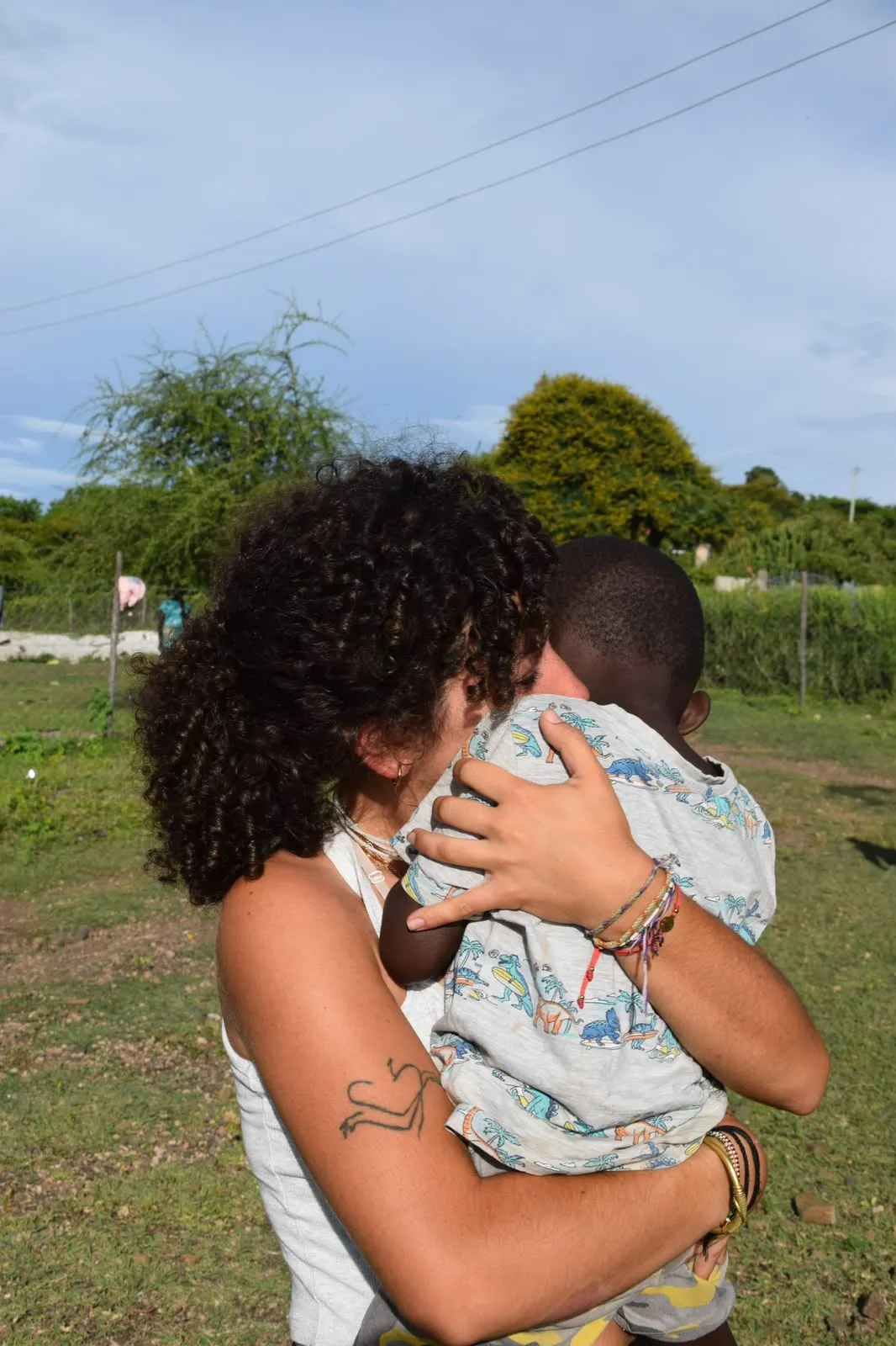 Una mujer abraza a un niño al aire libre.