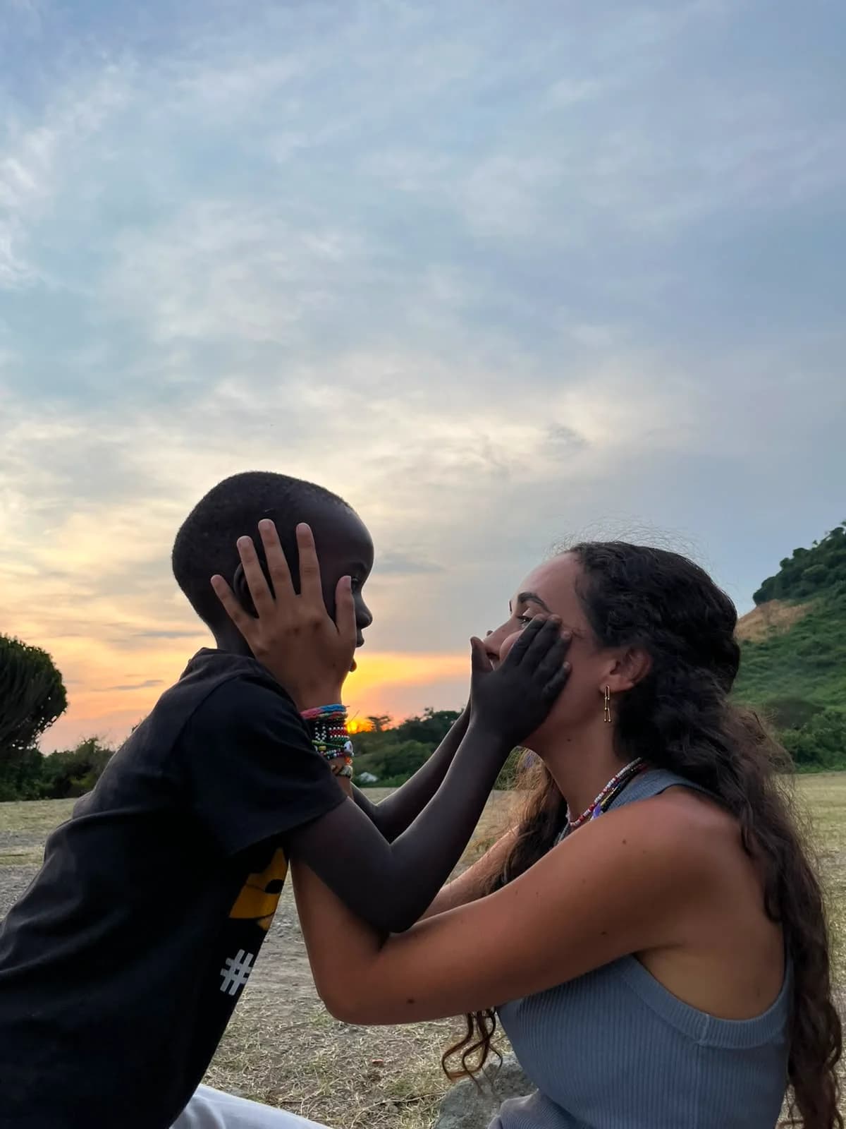 Una mujer y un niño se acarician las mejillas al aire libre.