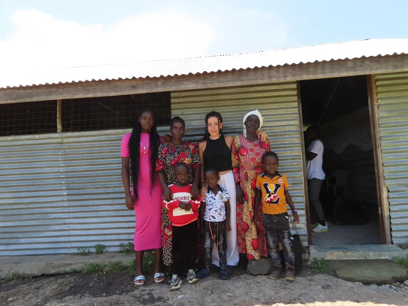 Un grupo de mujeres y niños reunidos delante de una casa.